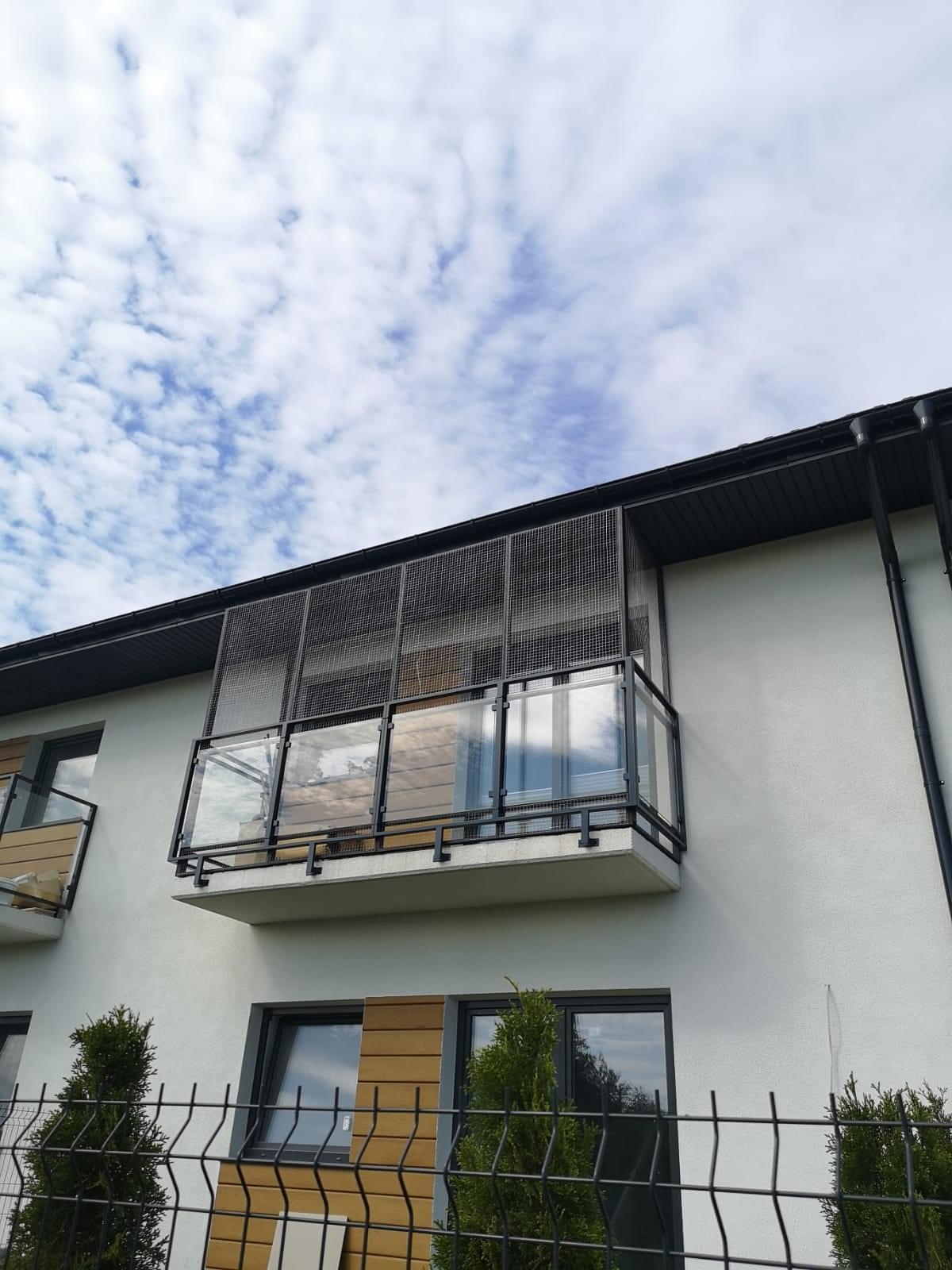 widok od zewnątrz na zabezpieczony stalowa siatką balkon
