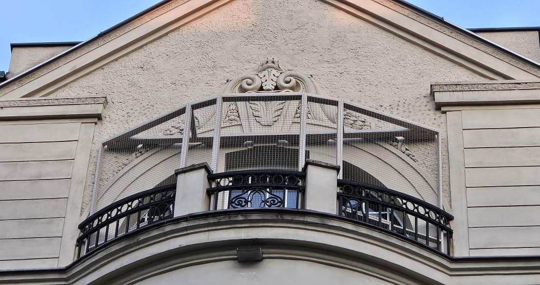 widok z dołu na zabezpieczony balkon w zabytkowej kamienicy
