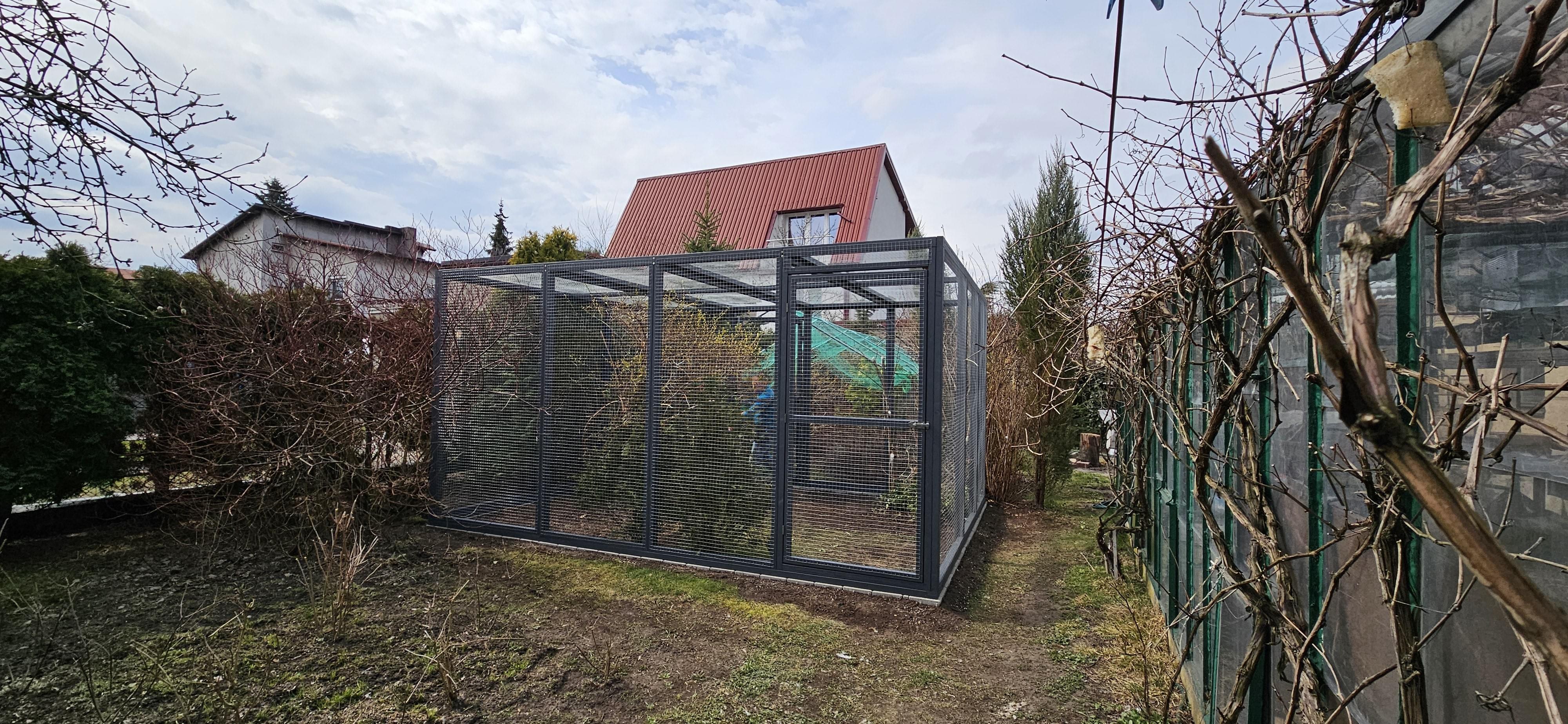 widok na dom do którego przylegają woliery na całej szerokości ściany